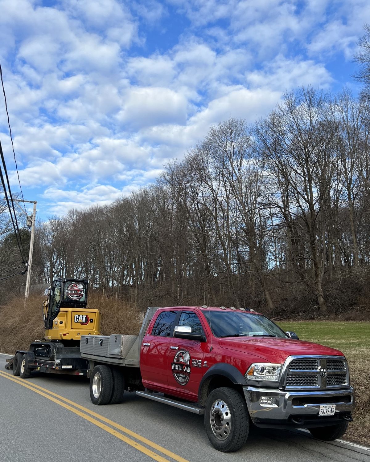 White Oak flatbed hauling a CAT mini excavator to a Dutchess County job